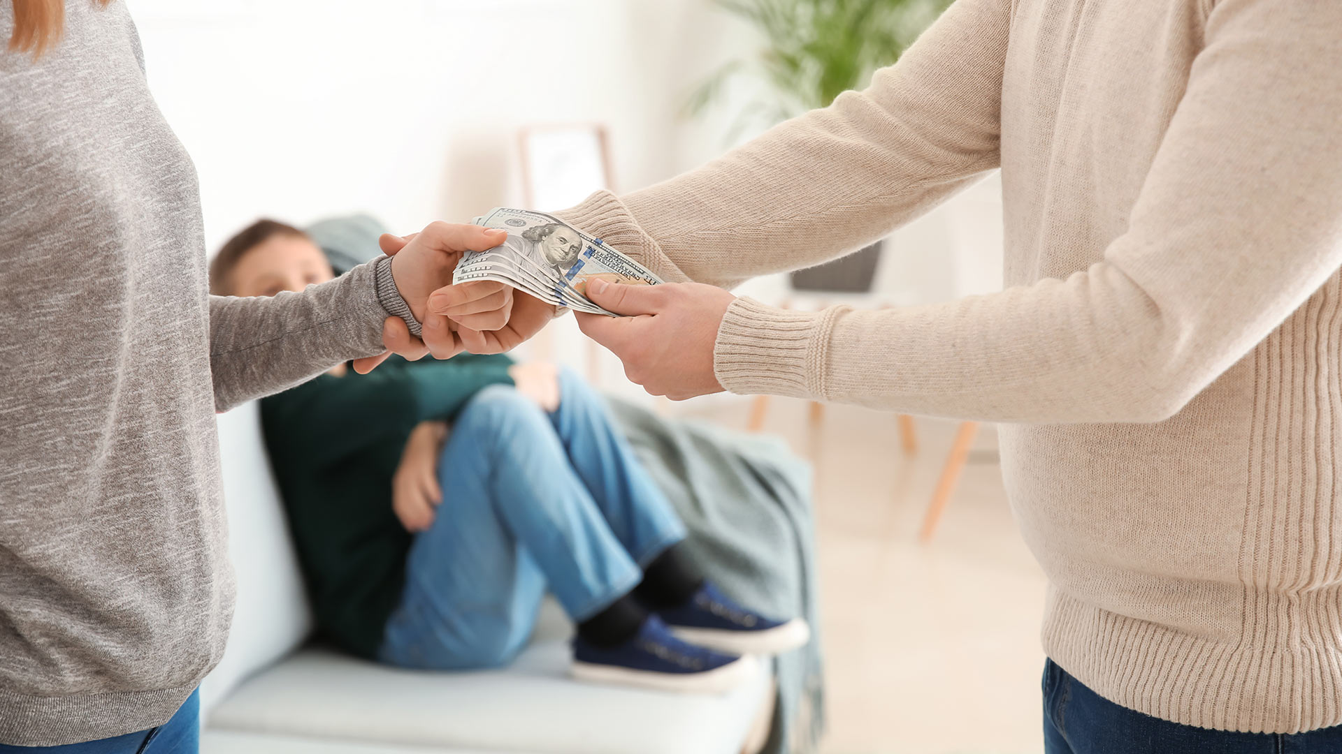 divorced couple exchanging money while son looks on from couch mesa az